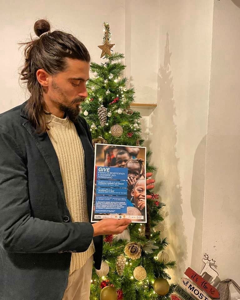 Giacomo tiene in mano la locandina dell'evento GIVE